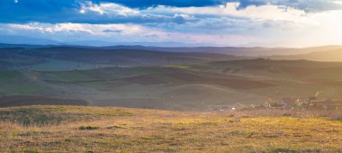 Yazın başında yeşil tepelerin üzerinde gün batımı.
