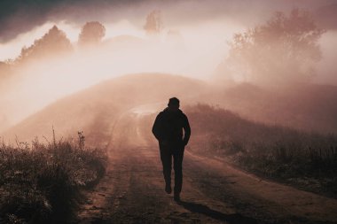 Sisli bir sonbahar manzarasında yürüyen bir adam