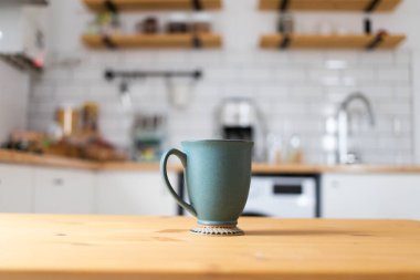 green coffee cup on kitchen table blurred kitchen in background