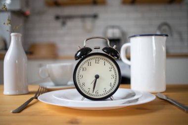 intermittent fasting concept alarm clock on kitchen table