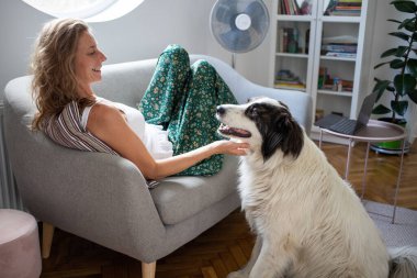 woman and white dog relaxing on sofa