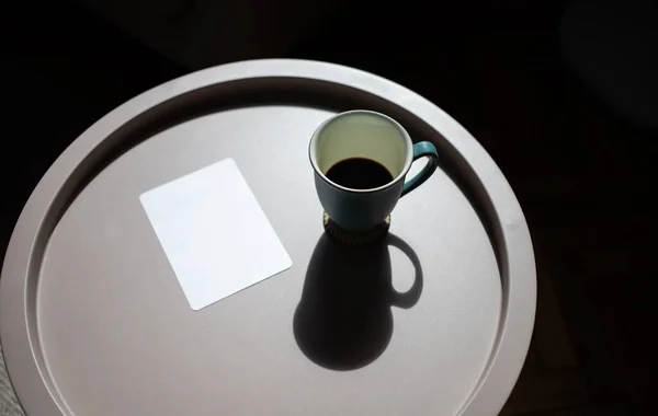 Φλιτζάνι Καφέ Και Κενή Κάρτα Στο Τραπέζι Στο Σκληρό Φως — Φωτογραφία Αρχείου