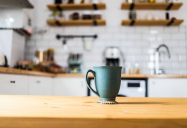 green coffee cup on kitchen table blurred kitchen in background