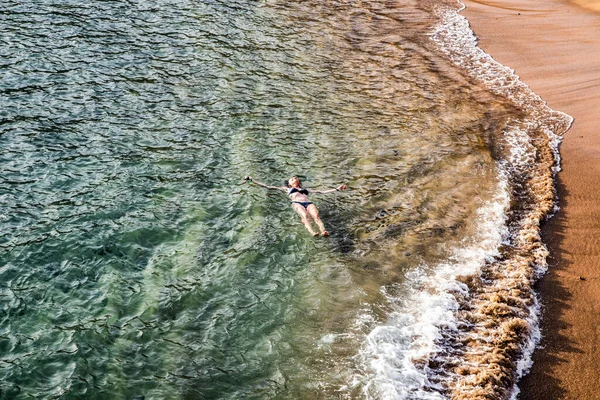 top view of woman floating in the sea near sandy beach