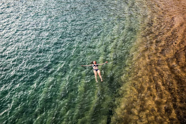 top view of woman floating in the sea near sandy beach
