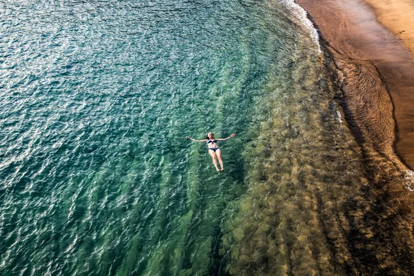 top view of woman floating in the sea near sandy beach