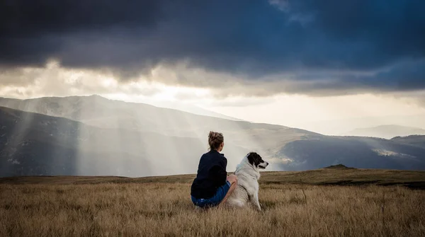 woman and dog watching amazing panorama of heavenly lights at sunset in high mountains