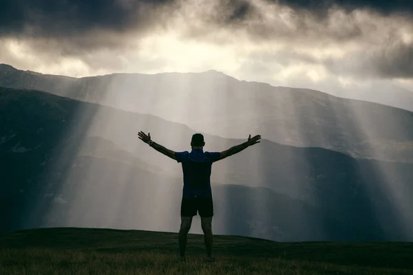 man silhouette against heavenly lights in mountains freedom concept