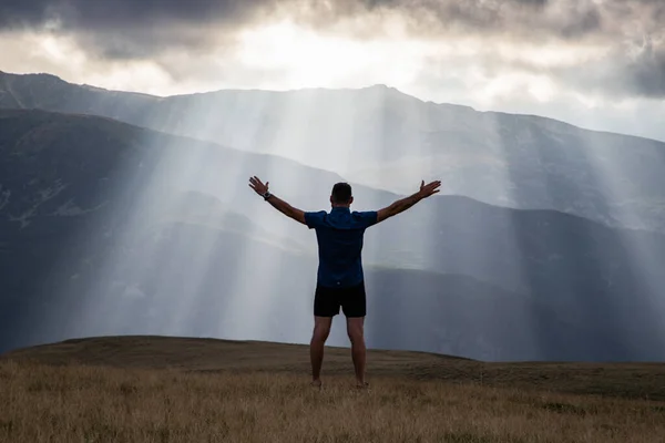 man silhouette against heavenly lights in mountains freedom concept