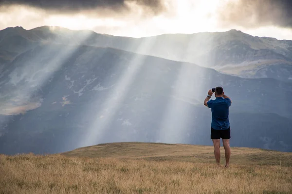 man taking photos of heavenly lights in mountains