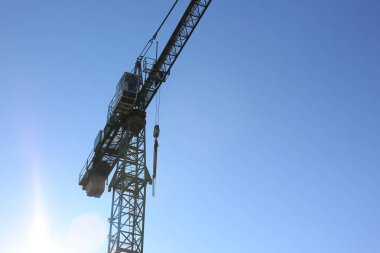 Mavi gökyüzüne karşı inşaat vincinin silueti.