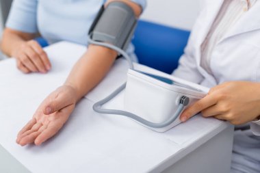 Beyaz önlüklü doktorun, kadının kan basıncını ölçtüğü görüntüler.