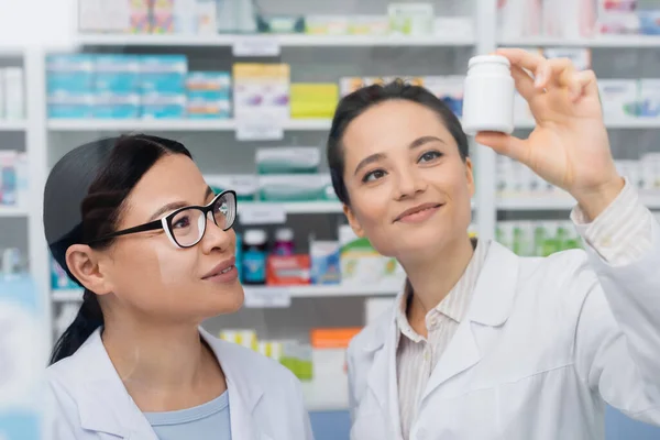 Alegre Farmacéutico Blanco Abrigo Celebración Botella Cerca Asiático Colega Gafas — Foto de Stock