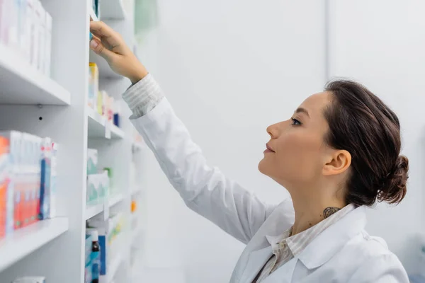Tattooed Apothecary White Coat Reaching Shelf Medication Drugstore — Stock Photo, Image