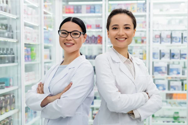Веселі Міжрасові Фармацевти Білих Пальто Стоять Схрещеними Руками Аптеці — стокове фото