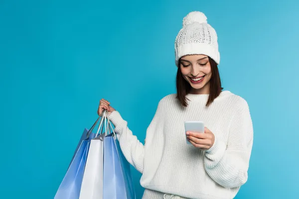 Mladá Žena Pletených Šatech Pomocí Smartphonu Držení Nákupních Tašek Izolovaných — Stock fotografie