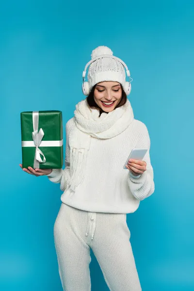 Smiling Woman Headphones Warm Clothes Using Cellphone Holding Gift Isolated — Stock Photo, Image