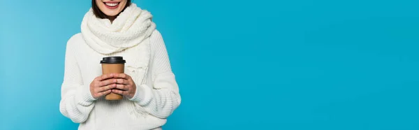 暖かいスカーフを保持する幸せな女性の作物のビューは青 バナーに隔離されたテイクアウトドリンク — ストック写真