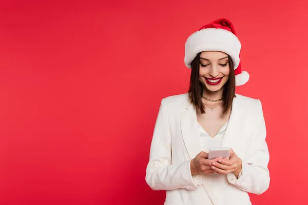 Positive Frau Mit Weihnachtsmannmütze Und Weißer Jacke Mit Handy Auf — Stockfoto