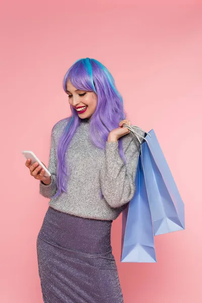 快乐的女人 用智能手机染发 手里拿着粉色的购物袋 — 图库照片