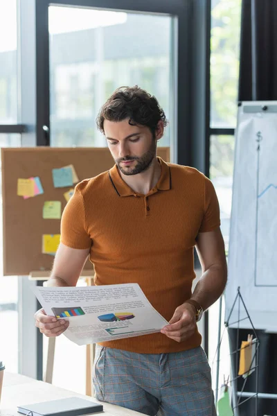 Empresario Mirando Papel Con Gráficos Mientras Trabaja Oficina — Foto de Stock