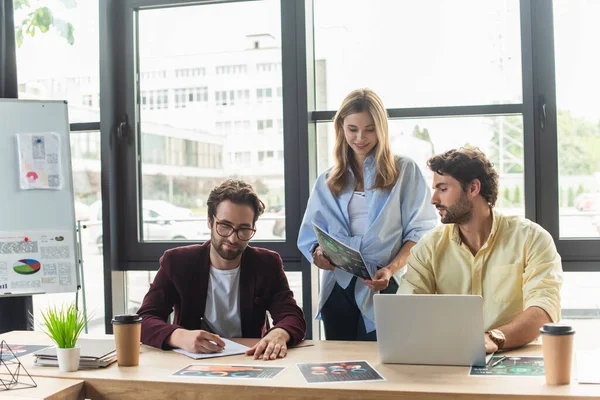 Glimlachende Zakenvrouw Met Document Buurt Van Zakenmannen Met Laptop Kantoor — Stockfoto