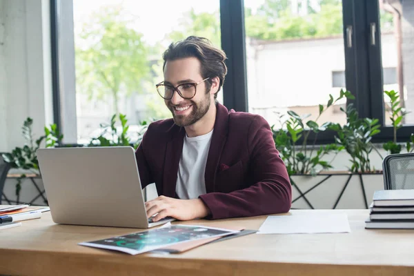 Positiv Affärsman Med Bärbar Dator Nära Dokument Och Anteckningsböcker Kontoret — Stockfoto