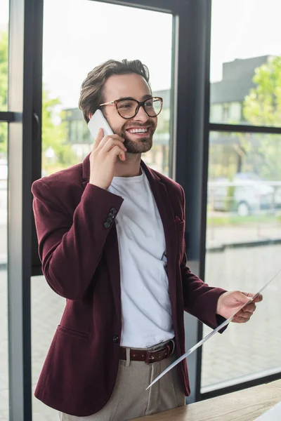 Hombre Negocios Sonriente Sosteniendo Papel Hablando Teléfono Inteligente Oficina — Foto de Stock