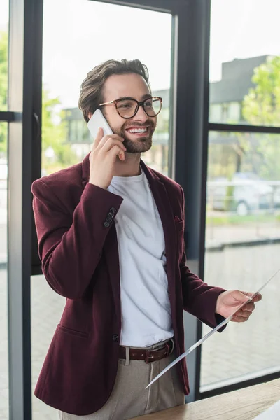 Uśmiechnięty Biznesmen Trzymający Papier Rozmawiający Smartfonie Biurze — Zdjęcie stockowe