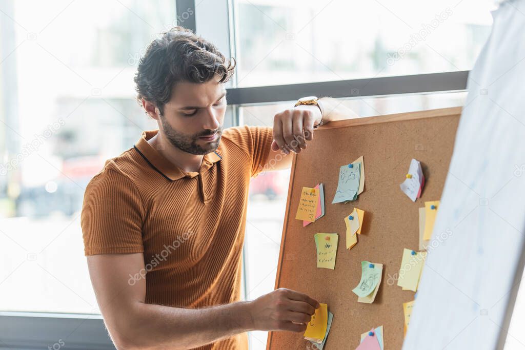 Businessman working with sticky notes on board in office 