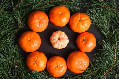 flat lay with ripe tangerines near golden christmas balls near fir branches clipart