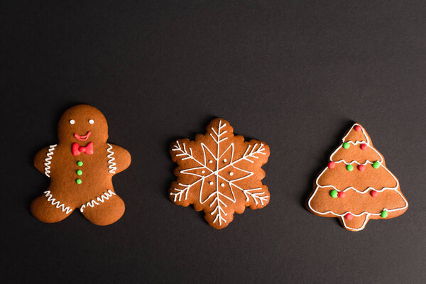 top view of different shapes gingerbread cookies on black