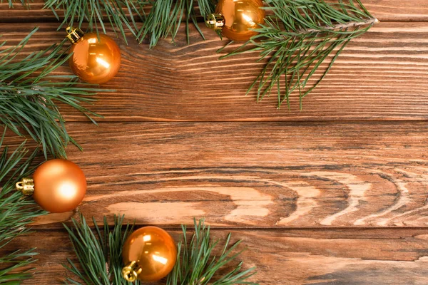 在木制表面的枞树枝头附近 有一个扁平的 金黄色的圣诞球 — 图库照片