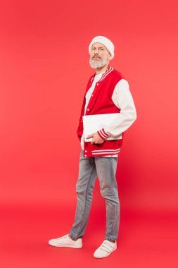 Tam boy, orta yaşlı, Noel Baba şapkalı, elinde dizüstü bilgisayarı olan bir serbest yazar.