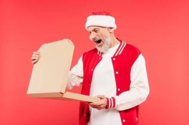 Noel Baba şapkalı orta yaşlı adamın elinde kırmızı kutuda izole edilmiş pizza kutusu var.