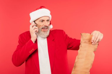 Noel Baba şapkalı olgun bir adam el sanatları kağıdında mektup okurken akıllı telefonda kırmızı üzerine izole edilmiş bir şekilde konuşur.
