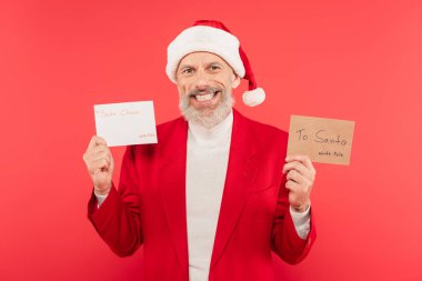 Şapkalı olgun bir adam, elinde bir zarf ve Noel Baba 'ya yazılmış bir mektup tutuyor.