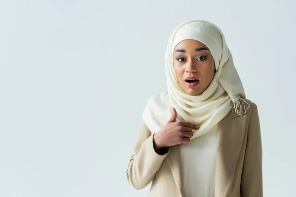 穿着头巾的穆斯林妇女惊讶地指着自己孤零零地躺在灰色的衣服上 — 图库照片
