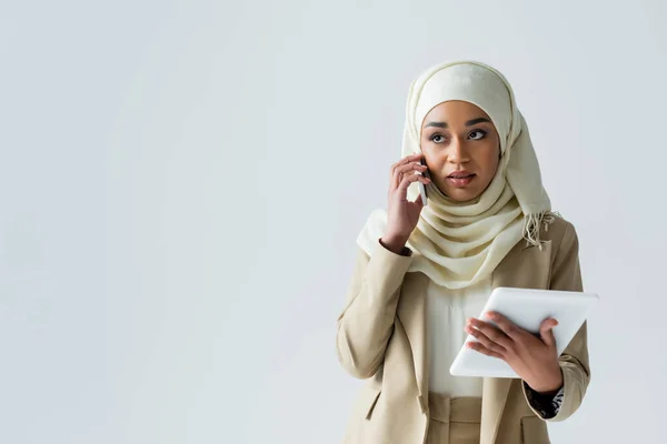 Молодая Мусульманка Хиджабе Держит Цифровой Планшет Разговаривает Смартфоне Изолированы Серый — стоковое фото