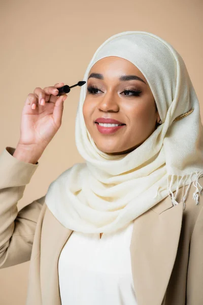 Gelukkig Moslim Vrouw Hijab Aanbrengen Mascara Met Borstel Geïsoleerd Beige — Stockfoto