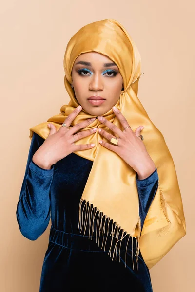 young muslim woman in hijab and velvet blue dress isolated on beige