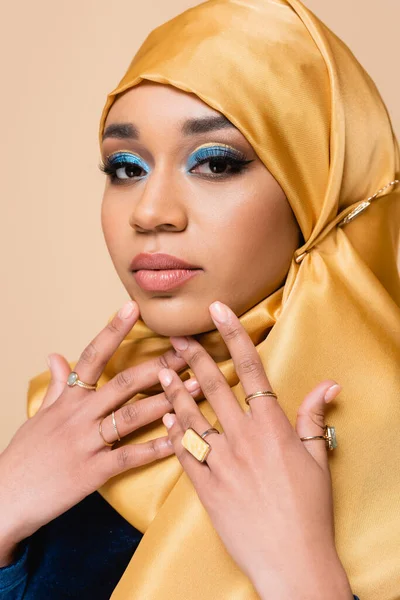 Muzułmanka Hidżabie Jasnym Makijażem Złotymi Obrączkami Patrząca Aparat Odizolowany Beżu — Zdjęcie stockowe