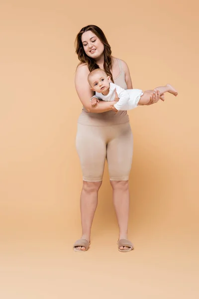 Feliz Más Tamaño Madre Sosteniendo Bebé Niña Sobre Fondo Beige —  Fotos de Stock