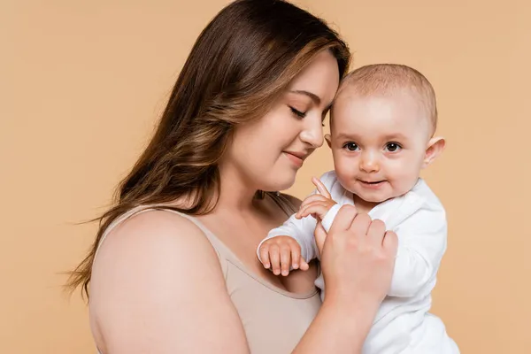 Brünette Frau Mit Geschlossenen Augen Hält Baby Isoliert Auf Beige — Stockfoto