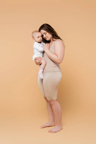 Pleine Longueur Mère Taille Tenant Bébé Fille Sur Fond Beige — Photo