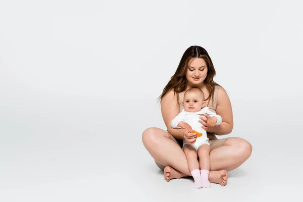 Neşeli Vücut Pozitifliği Gri Arka Planda Otururken Bebek Kızına Sarılıyor — Stok fotoğraf