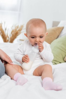 Bebek elinde sütle şişeyle yatağında bekliyor. 