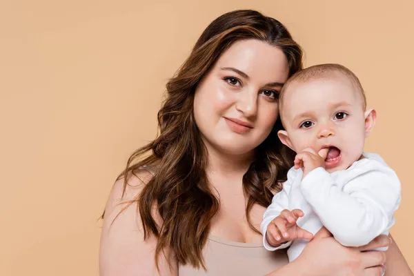 Bonito Tamanho Mãe Segurando Bebê Olhando Para Câmera Isolada Bege — Fotografia de Stock