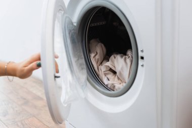 cropped view of woman opening washing machine with laundry clipart