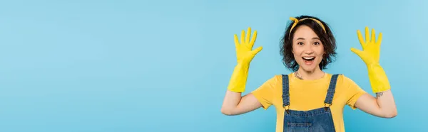 Erstaunt Hausfrau Zeigt Hände Gelben Gummihandschuhen Isoliert Auf Blau Banner — Stockfoto